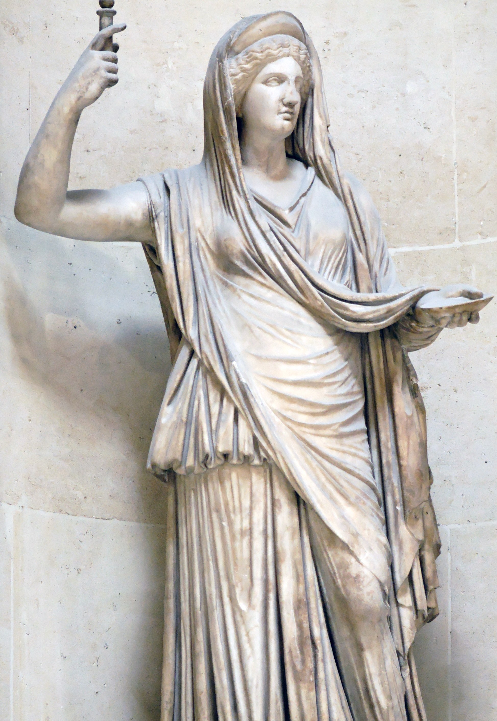 Marble statue of Hera as queen, standing veiled in a long chiton and himation with a diadem band across her brow, her raised right hand holding a sceptre and her extended left hand bearing a shallow offering dish.