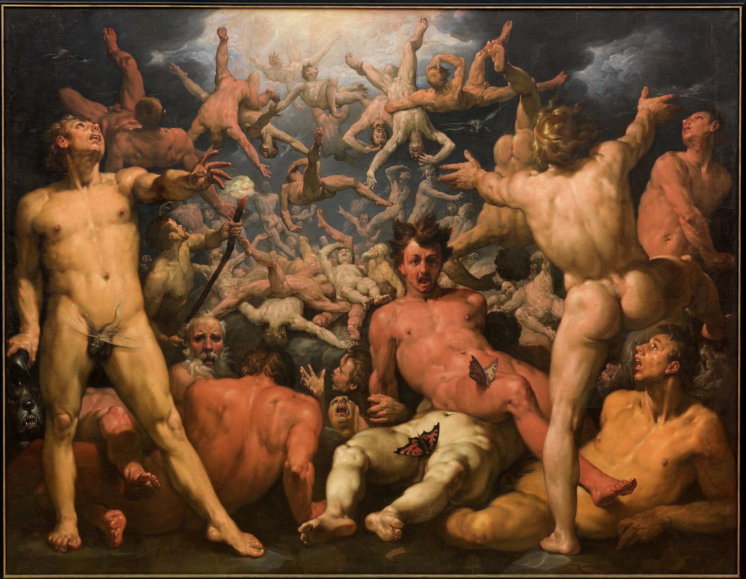 A dark, teeming Mannerist canvas of the defeated Titans hurled from the sky. From a luminous break in the storm-clouds at the top, a mass of muscular nude figures tumbles headlong and foreshortened into the depths, limbs flailing and faces contorted in terror. They pile into a heap of straining bodies across the foreground, ruddy and pale flesh tangled together; one massive figure sprawls face-up at the centre, mouth open in a scream, his hair standing on end. At the lower left a standing youth grips a burning torch while a black hound's fanged head snarls beside him, and a few small butterflies and insects — the painter's emblems of the fleeting — rest on the fallen limbs.